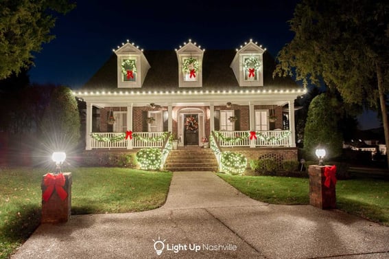 Holiday lighting display with greenery